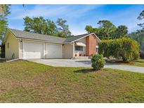 Charming home featuring a two-car garage, well-manicured lawn, and mature trees providing ample shade at 17380 Shirley Ave, Port Charlotte, FL 33948