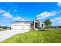 Inviting single-Gathering home featuring a three-car garage, modern design, and manicured lawn at 24166 Colima Ct, Punta Gorda, FL 33955