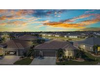 Beautiful exterior view of home with a well-manicured lawn, two-car garage, and serene water view at sunset at 24371 Westgate Blvd, Port Charlotte, FL 33980