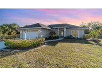 Charming single-story home featuring a manicured lawn, attached garage, and a welcoming walkway to the front door at 422 Ravenswood Blvd, Port Charlotte, FL 33954