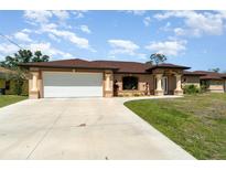 Charming single-story home with a manicured lawn and a spacious two car garage on a sunny day at 5125 Ariton Rd, North Port, FL 34288