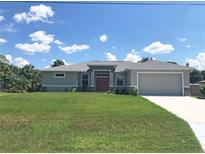 Charming single-story home with manicured lawn, neutral paint, and attached garage with an inviting exterior elevation at 1182 Yorkshire St, Port Charlotte, FL 33952