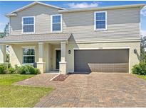 Inviting two-story home featuring a brick driveway, neutral siding, and an attached two-car garage at 15172 Mcgraw Ave, Port Charlotte, FL 33953
