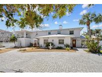 Charming two-story home with lush landscaping, brick driveway, and a quaint fountain at 6112 Gnarled Oak Dr, Englewood, FL 34223