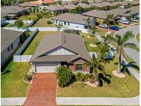 Aerial view of a well-maintained home with a brick driveway, complemented by palm trees and a white fenced backyard at 15288 Mille Fiore Blvd, Port Charlotte, FL 33953