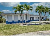 Inviting single-story home with vibrant blue trim and well-manicured lawn adorned with lovely palm trees at 234 Tait Se Ter, Port Charlotte, FL 33952