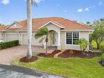 Charming single-story home featuring a well-manicured lawn, brick driveway, and a terracotta roof at 16308 Sunset Palms Blvd # 1702, Punta Gorda, FL 33955