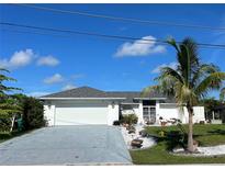 Charming single-story home boasts a well-manicured lawn, palm tree, and attached two-car garage at 2095 Ellery St, Port Charlotte, FL 33952