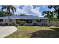 Charming home featuring a well-maintained lawn, mature trees, and a freshly painted exterior in a serene setting at 131 Spring Lake Nw Blvd, Port Charlotte, FL 33952