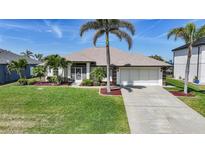 Charming single-story home with a well-manicured lawn, beautiful landscaping, and a two-car garage at 15538 Aqua Cir, Port Charlotte, FL 33981