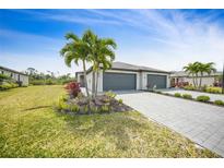 Inviting exterior elevation with a three-car garage, well-manicured lawn, and lush tropical landscaping at 2232 Bonito Way, Port Charlotte, FL 33953