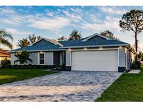 Charming single-Gathering home featuring a brick driveway, a two-car garage, and lush green lawn at 27260 Porto Nacional Dr, Punta Gorda, FL 33983