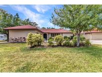 Charming single-story home with a well-manicured lawn and lush landscaping, complemented by a red tile roof at 27475 Cleveland Ave, Punta Gorda, FL 33982