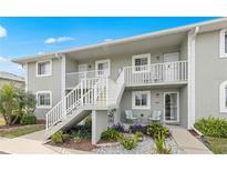 Charming condo with beautiful landscaping, white railings, and a cozy seating area on the ground floor at 3310 Loveland Blvd # 1906, Punta Gorda, FL 33980