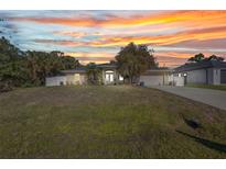 Charming single-story home with a well-manicured lawn and beautiful landscaping at sunset at 4331 Marcella Ter, North Port, FL 34286
