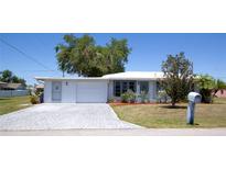 Charming home featuring a brick driveway, a well-maintained lawn, and a cheerful light blue front door at 458 Azalea Nw Ave, Port Charlotte, FL 33952