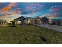 Beautiful single-story home featuring a three-car garage, well-manicured lawn, and inviting landscaping at 474 Rio De Janeiro Ave, Punta Gorda, FL 33983