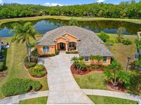 Beautiful house with manicured lawn, mature trees, and serene lake view, creating a peaceful and inviting atmosphere at 624 Planters Manor Way, Bradenton, FL 34212
