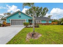 Charming home with a lush green lawn, mature landscaping, and blue exterior at 1137 Ponderosa Rd, Venice, FL 34293