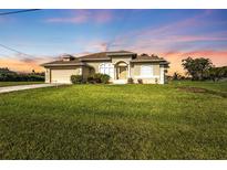 Charming single-story home with a lush green lawn and well-maintained landscaping at 235 Tournament Rd, Rotonda West, FL 33947