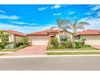 Charming single-story home featuring a red tile roof, lush landscaping, and a brick driveway, all under a bright blue sky at 264 Soliera St, Nokomis, FL 34275