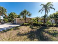Charming single-story home featuring a well-manicured lawn, mature landscaping, and a private gated entrance at 4438 Meager Cir, Port Charlotte, FL 33948