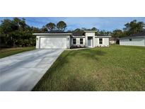 Charming single-story home featuring a well-manicured lawn and attached two-car garage with neutral paint at 5354 Wagon Wheel Dr, North Port, FL 34291
