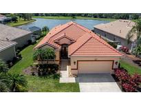 Charming single-Gathering home with a red tile roof, lush landscaping, and a well-maintained lawn at 5733 White Jasmine Way, North Port, FL 34287