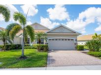 Charming single-story home featuring a paved driveway, lush landscaping, and an attached two-car garage at 1940 Scarlett Ave, North Port, FL 34289