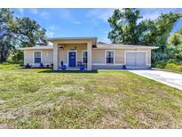 Charming single-story home featuring a blue front door and well-maintained lawn with mature trees and a one car garage at 2679 Pascal Ave, North Port, FL 34286