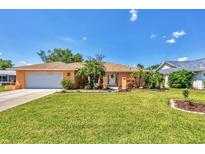 Charming single-story home featuring a manicured lawn and lush tropical landscaping at 3287 Meadow Run Cir, Venice, FL 34293