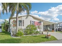 Charming home with covered parking, lush landscaping, and an American flag at 724 Blackburn Blvd, North Port, FL 34287