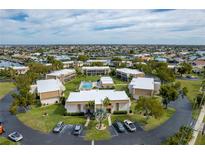 Wide aerial view of condos with central pool, circular drive, and ample parking in a residential neighborhood at 1080 Bal Harbor Blvd # 10C, Punta Gorda, FL 33950
