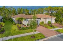Charming single-story home with a well-manicured lawn, brick driveway, and elegant landscaping at 1352 Raspberry Dr, North Port, FL 34289