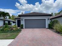 Charming single-story home featuring a brick driveway, attached two-car garage, and lush landscaping at 1352 Raspberry Dr, North Port, FL 34289