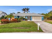 Charming single-story home featuring a two-car garage, lush landscaping, and a well-manicured lawn at 17342 Foremost Ln, Port Charlotte, FL 33948