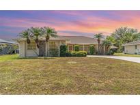 Charming one-story home featuring mature landscaping with palm trees and a well-maintained front yard at 18379 Edgewater Dr, Port Charlotte, FL 33948
