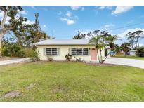 Charming single-story home featuring a well-maintained lawn and inviting pink front door at 212 Gulf Ave, Nokomis, FL 34275