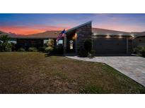 Charming single-story home featuring stone accents, manicured lawn, paver driveway, and attached garage at 2304 Bonn Ct, Punta Gorda, FL 33983