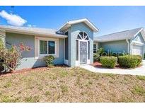 Well-maintained single-story home with tidy landscaping, a two-car garage, and a cozy front entrance at 23482 Moreland Ave, Port Charlotte, FL 33954