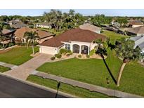 Well maintained single-story home with a lush lawn, mature landscaping, and a brick paved driveway at 2363 Jasmine Way, North Port, FL 34287