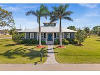 Charming home featuring a metal roof, lush landscaping, and a welcoming blue front door at 303 W Grace St, Punta Gorda, FL 33950