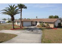 Charming single-story home featuring a stone accent, well-manicured lawn, and a circular driveway leading to an attached garage at 474 Elm Nw Ave, Port Charlotte, FL 33952