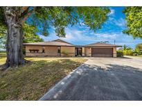Spacious, tan home with a two-car garage, long driveway, and mature trees in a landscaped yard at 3123 David St, Punta Gorda, FL 33982