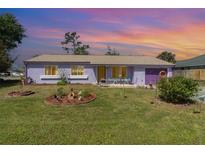 Charming single-story home with a colorful exterior, manicured lawn, and decorative garden beds at 402 Cicero Nw St, Port Charlotte, FL 33948