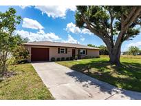 Charming single-story home with a well-maintained yard and a large tree providing ample shade at 661 Athos Ter, Port Charlotte, FL 33952