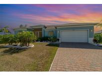 Charming single-story home featuring a manicured lawn and a two-car garage with a brick paver driveway at 8117 Thruso Rd, Port Charlotte, FL 33981
