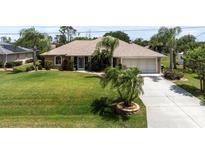 Charming single-story home featuring well-manicured lawn and mature palm trees, creating a welcoming curb appeal at 1240 Alpinia Rd, North Port, FL 34288