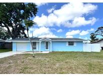 Charming blue single-story home with a well-manicured lawn and a beautiful tree at 2600 Mohegan Rd, Venice, FL 34293