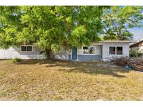 Modest one-story home exterior with tree cover and muted gray brick facade near entryway at 2677 Martin St, Sarasota, FL 34237